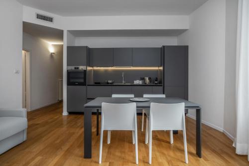 a kitchen with a black table and white chairs at Bertamini Apartments in Nago-Torbole