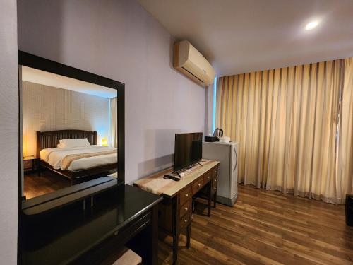 a hotel room with a bed and a desk with a television at August Residence in Bangkok