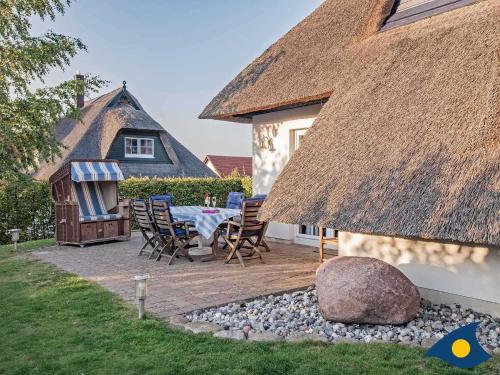 a patio with a table and chairs and a thatch roof at Haus Klabautermann in Heringsdorf