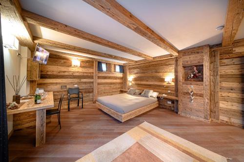 a bedroom with wooden walls and a bed and a desk at Hotel Ambrosini in Aprica