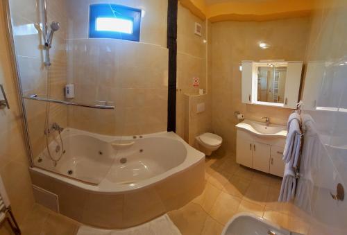 a bathroom with a tub and a toilet and a sink at Hotel Garten in Slavonski Brod