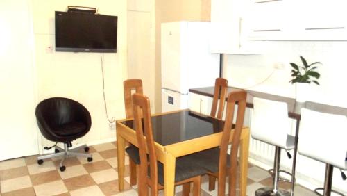 uma cozinha com uma mesa e cadeiras e uma televisão em Nice Double Room London Rental em Londres