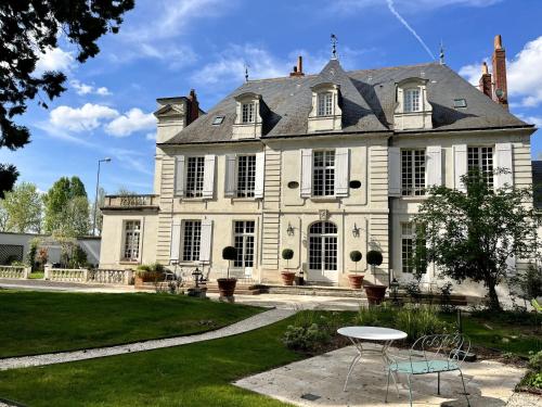 una gran casa blanca con una mesa delante en Le Clos du Roc en Montlouis-sur-Loire