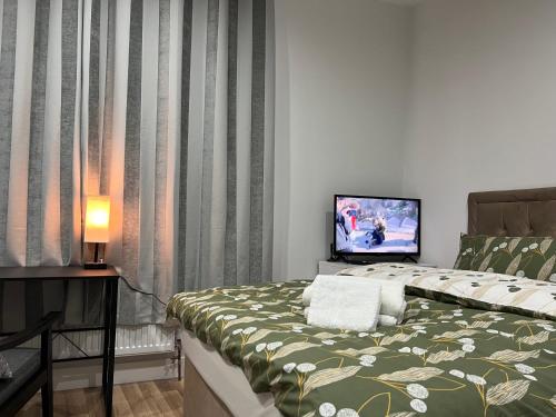 a bedroom with a bed with a television on it at La Vie - Entire Apartment - Next to Central District Elizabeth line Tube Station - Near Central London & Wembley in Ealing