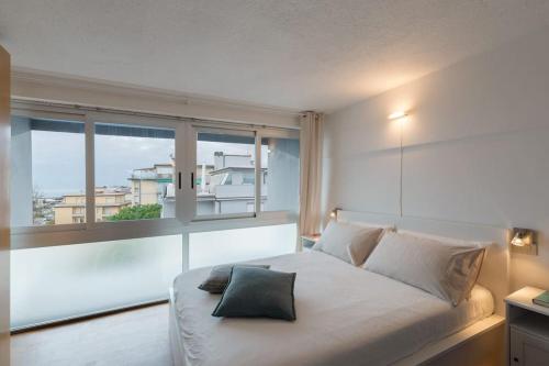 a bedroom with a white bed with a large window at [Duca d'Aosta - il soffio del mare] in Viareggio
