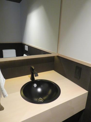a bathroom counter with a black sink and a mirror at Kashoutei Hanaya in Noboribetsu