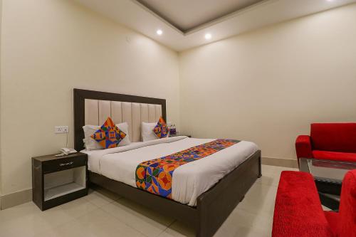 a bedroom with a bed and a red chair at FabHotel AGK in Haridwār