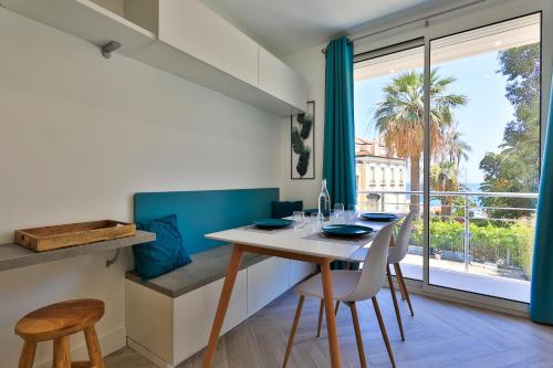 jadalnia ze stołem i krzesłami oraz dużym oknem w obiekcie Le Vallaya Suites & Spa w Mentonie