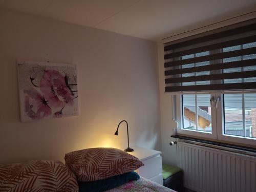 a bedroom with a bed and a window with a lamp at Ser's Studio Orange in Maastricht