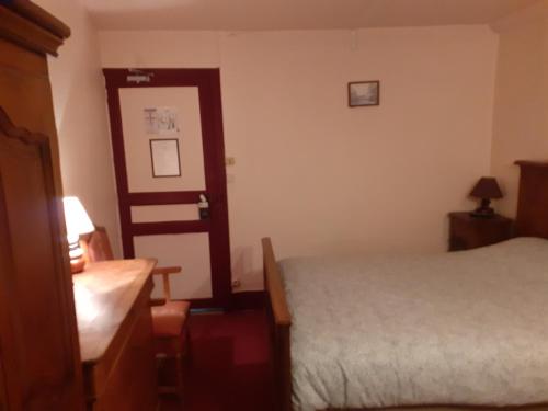 a bedroom with a bed and a desk and a mirror at Le Grand Cerf in Nonancourt