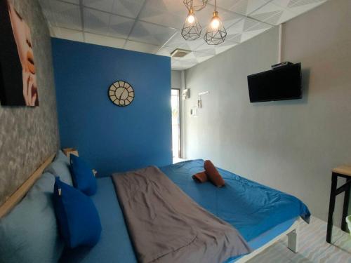 a bedroom with a blue bed with a clock on the wall at I-Talay Zone Sea in Ko Samed