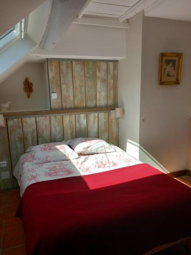 een slaapkamer met een groot bed en een rode deken bij le Portail bleu in Châtres