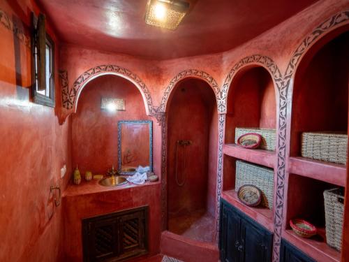 a bathroom with red walls and a sink and shelves at Dar Ben Saleh in Marrakesh