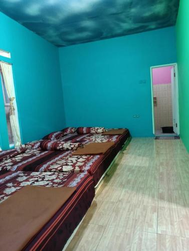 duże łóżko w pokoju z niebieskimi ścianami w obiekcie Faviliun haikal w mieście Cisarua