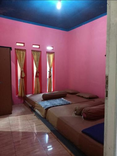 2 łóżka w pokoju z różowymi ścianami w obiekcie Faviliun haikal w mieście Cisarua