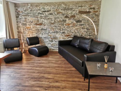 a living room with a black couch and a brick wall at Schöne, sonnige Parterrewohung 3 Zi. mit Garten in Poschiavo