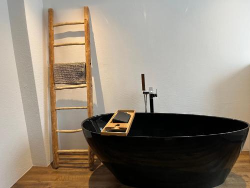 una vasca da bagno nera in una stanza con una scala di Schöne, sonnige Parterrewohung 3 Zi. mit Garten a Poschiavo