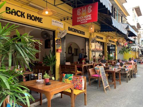 un restaurant avec des tables et des chaises en bois devant lui dans l'établissement Back Home Backpackers, à Bangkok