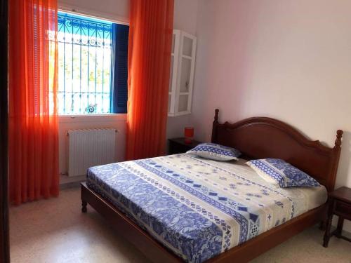1 dormitorio con 1 cama y una ventana con cortinas de color naranja en Hammamet northern border (Nabeul), 200m from sea and downtown, en Nabeul