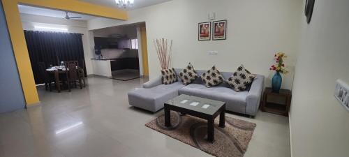 バンガロールにあるBulande Comforts-Service Apartment ITPL Whitefieldのリビングルーム(ソファ、テーブル付)