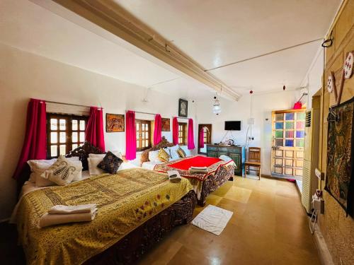 a bedroom with two beds and red curtains at Hotel Victoria in Jaisalmer