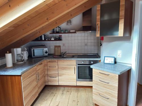 a kitchen with wooden cabinets and a stove top oven at Das Bergquartier - Ferienwohnung Krottenkopf in Oberau