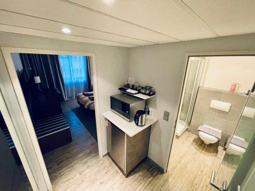 a hotel room with a microwave and a bathroom at 4* Boutique Zimmer am Düsseldorf Hafen + ÖPNV & TG in Düsseldorf
