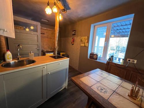 a kitchen with a sink and a window and a table at Private Farm Jakuzzi Sauna in the forest in Talsi
