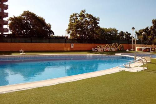 a large swimming pool in a yard with grass at Bajo con gran terraza en Ribera de Cabanes in Cabanes