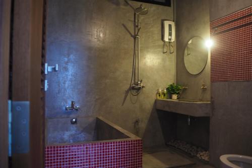 a bathroom with a pink tub and a sink at No.210 Maikhao Bedroom Studio in Ban Dan