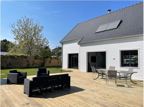 een patio met een tafel en stoelen en een gebouw bij Villa des églantiers baie de somme in Cayeux-sur-Mer