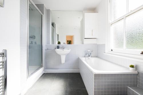 a white bathroom with a tub and a sink at The Bridge Flats in London