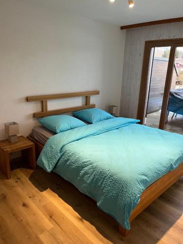 1 dormitorio con 1 cama grande con sábanas azules en Au village de Nax, ravissant 2 pièces et demi avec terrasse, en Nax