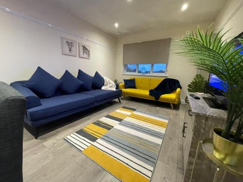 a living room with blue couches and a yellow couch at The Riverside in Alloa