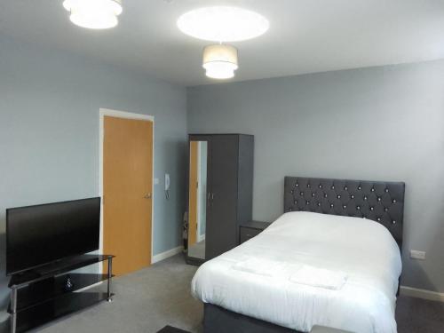 a bedroom with a bed and a flat screen tv at Piccadilly Apartments in Bradford