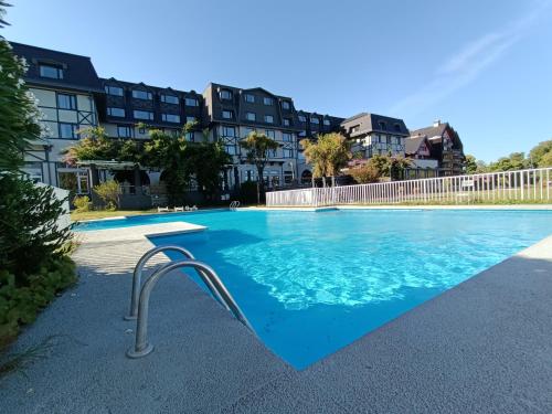 a swimming pool with blue water and buildings in the background at Hotel Enjoy Pucon in Pucón