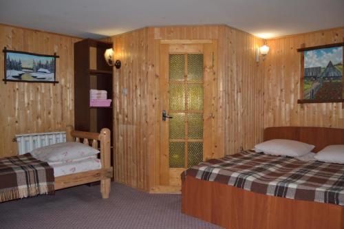 two beds in a room with wooden walls at Fortuna in Lazeshchyna
