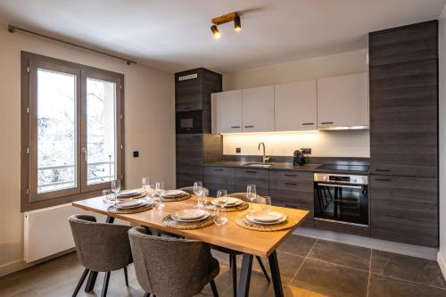une cuisine avec une table en bois et quelques chaises dans l'établissement Perle Blanche - Brand New 2 bedroom apartment perfectly located, à Chamonix-Mont-Blanc