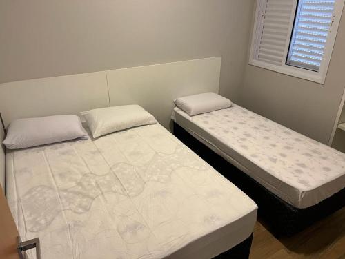 two twin beds in a room with a window at Apartamento Jardins Ubatuba in Ubatuba