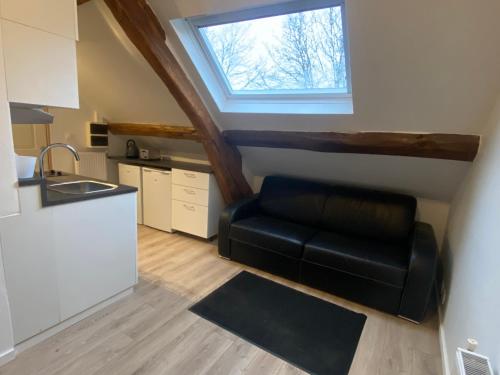 - une petite cuisine avec un canapé en cuir noir dans l'établissement 2 pièces les écuries du château, à Bonnelles