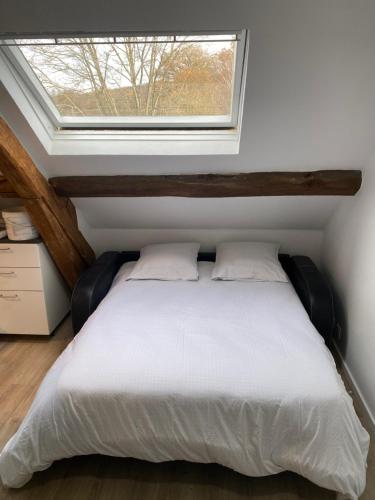 a bedroom with a white bed with a window at 2 pièces les écuries du château in Bonnelles