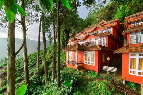 una casa roja en una colina con árboles en Tea Valley Resort, Munnar, en Munnar