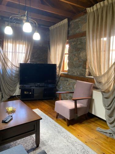 a living room with a tv and a chair and a table at Urban River House in Florina