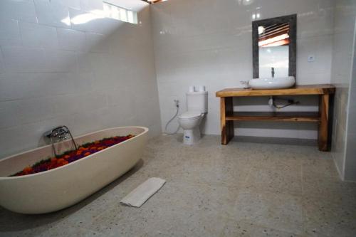 a bathroom with a tub and a sink and a toilet at Adil Villa & Resort in Ubud