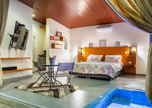 1 dormitorio con cama, mesa y piscina en Sunset Palm Lodge, en San Gil