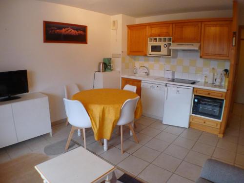 una cocina con mesa y sillas y una cocina con electrodomésticos blancos. en Appartement Samoëns, 3 pièces, 4 personnes - FR-1-629-101, en Samoëns