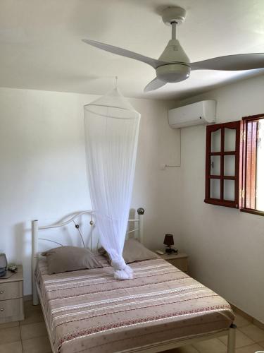 a bedroom with a bed with a ceiling fan at Villa Café - Appartement F2 à Sainte-Anne in Sainte-Anne