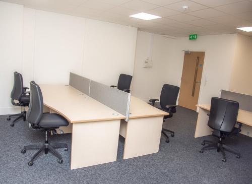 an office cubicle with two desks and chairs at Piccadilly Apartments in Bradford