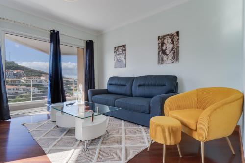 a living room with a blue couch and a glass table at Camara de Lobos Duplex Apartment by Holiday Rental Madeira in Câmara de Lobos