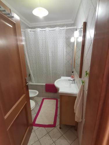 a bathroom with a sink and a toilet and a mirror at Studio acolhedor e confortável - Nazaré Waves in Nazaré